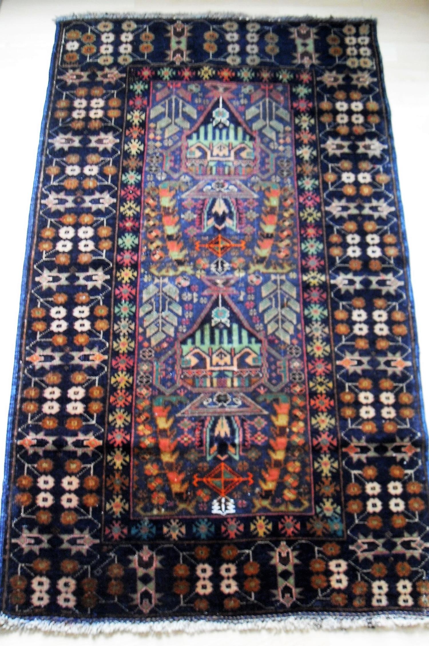 An Afghan hand-knotted blue-ground Balochi wool rug with multi-coloured isometric designs and