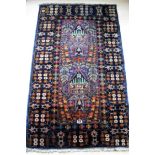 An Afghan hand-knotted blue-ground Balochi wool rug with multi-coloured isometric designs and