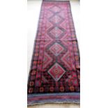 An Afghan hand-knotted Mashwani burgundy-ground wool runner with central diamond designs, single