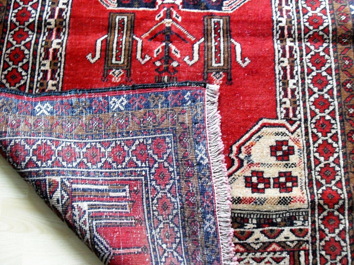 An Afghan hand-knotted burgundy-ground Balochi wool rug with multi-coloured isometric designs,