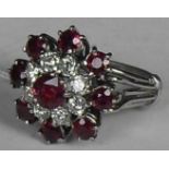 A target-style diamond and ruby cluster ring. Set with nine mixed-cut rubies, one measuring 5.4mm