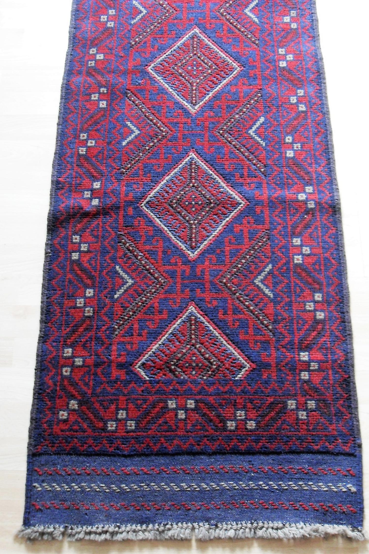An Afghan hand-knotted burgundy-ground Meshwani wool runner with short fringe, 60 x 249 cm in good