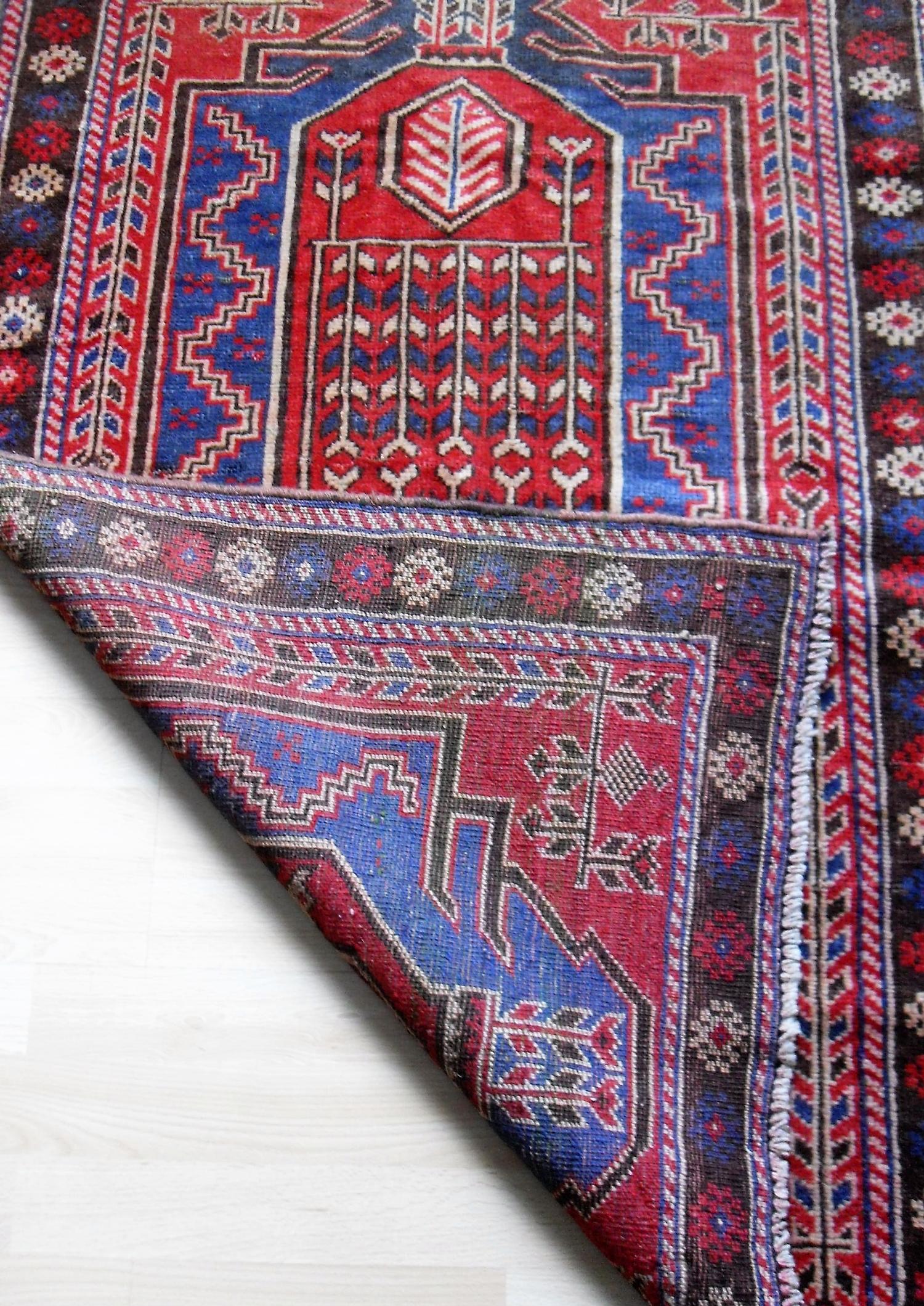 An Afghan hand-knotted scarlet-ground Balochi wool rug with multi-coloured isometric designs, double