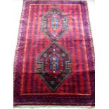 An Afghan hand-knotted burgundy-ground Herathi Balochi wool rug with multi-coloured designs,