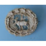 A mid 19th century oval Dieppe ivory brooch, the centre pierced and finely carved with a stag in a