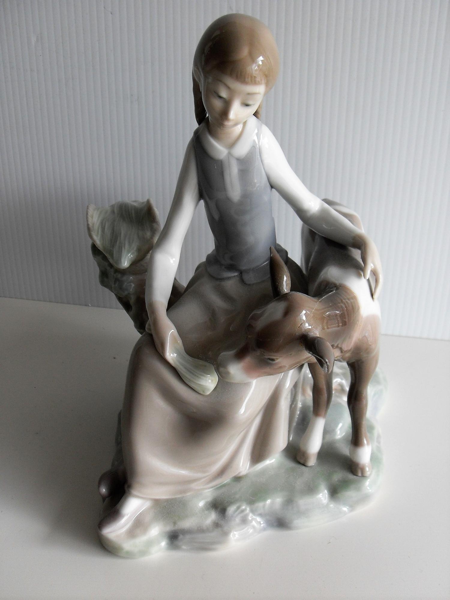 A Lladro figure of a seated young girl feeding a calf - repair to head and neck of calf