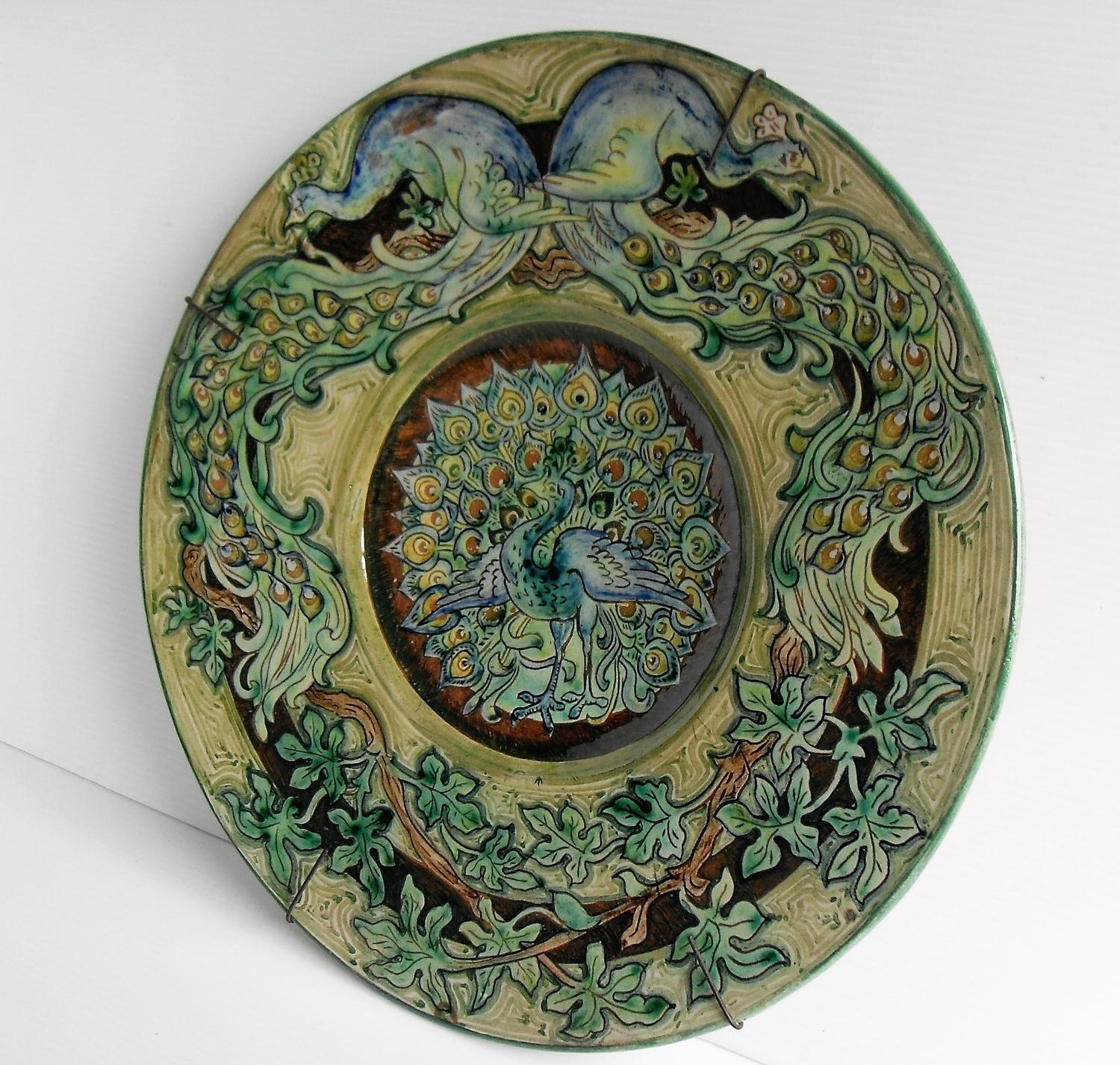 An Art Nouveau Della Robbia earthenware green-ground charger with stylized sgrafitto peacock designs