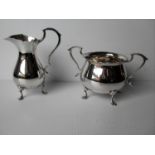 An Edwardian silver pear-shape cream jug on trefid feet with matching two-handled sugar bowl by