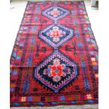 An Afghan hand-knotted Herathi Balochi burgundy-ground wool rug with multi-coloured isometric