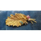 A mid 20th century 18ct gold brooch in the form of a leaf with mounted turquoise, garnet,