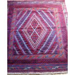 An Afghan tribal hand-knotted burgundy Kazak wool rug with multi-coloured lozenge decoration, double