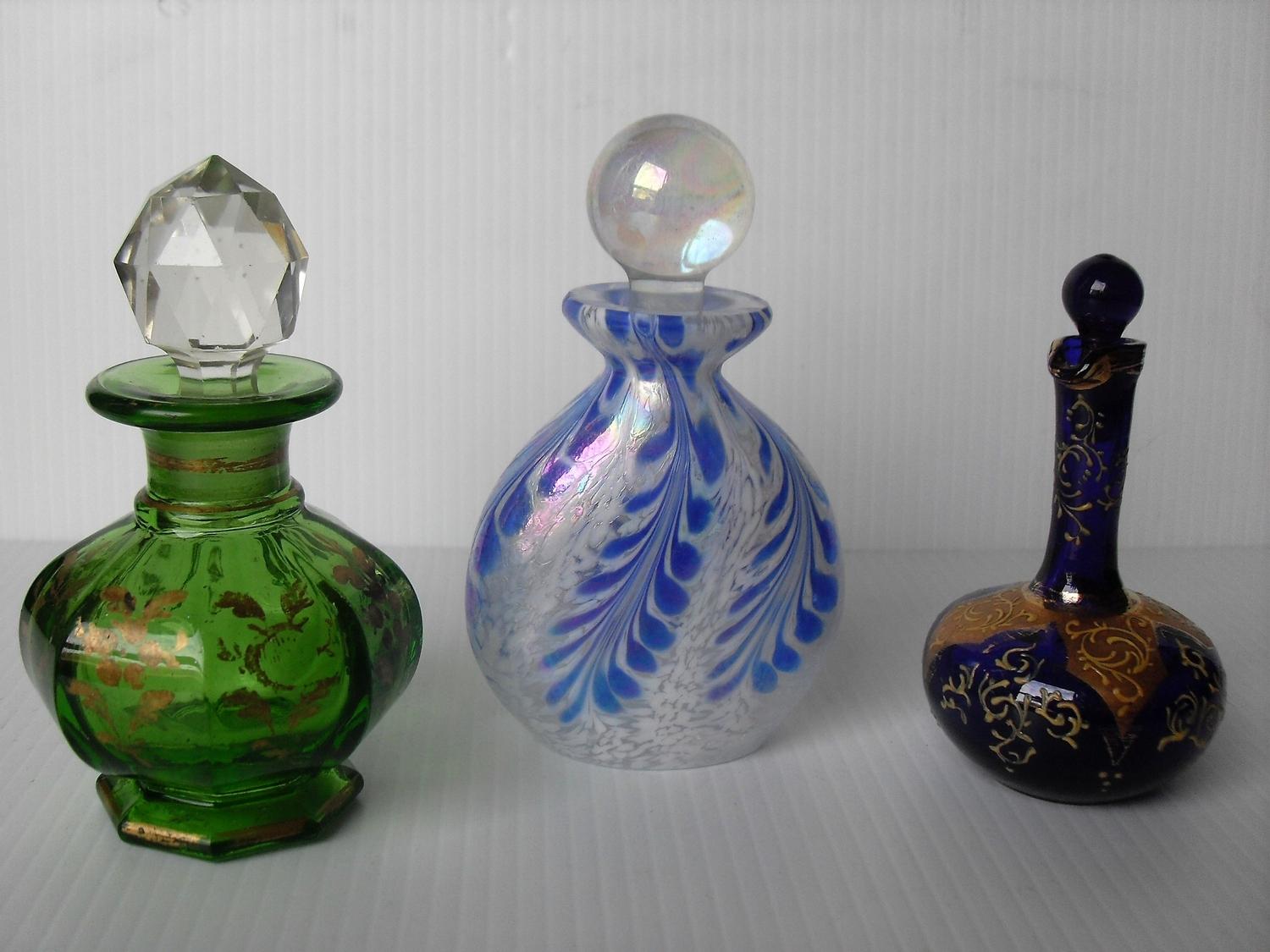 Three various glass scent bottles and a small hand mirror with painted floral decoration, 10 - 12 cm