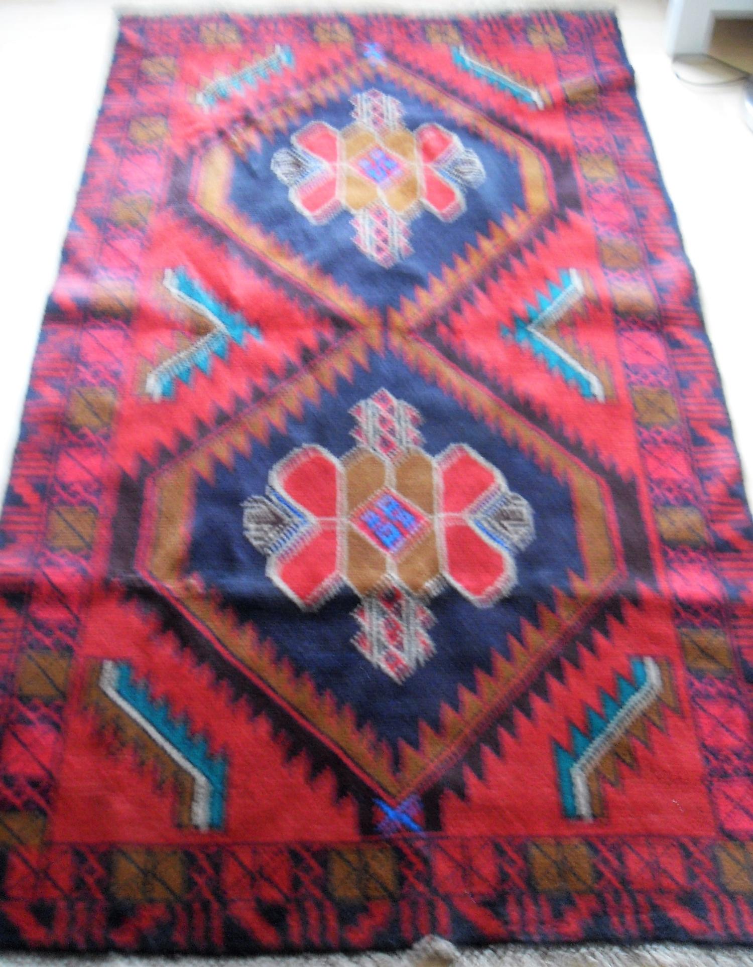 An Afghan wool Hearthi Balochi burgundy-ground hand knotted rug with multicoloured isometric