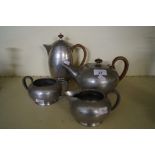A Tudoric pewter four piece tea service, the teapot and hot water pot with wicker handle,
