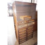 A mid 20th Century haberdashery cabinet, having an assortment of glazed cupboard doors.