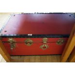 A vintage red trunk containing an assortment of sundry items.