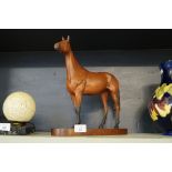 A Beswick model of Red Rum finished in a matt glaze, raised on oval wooden plinth base.