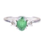 An emerald and diamond three stone ring The oval-shaped emerald,