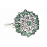 An emerald and diamond target cluster ring The circular-cut emerald to a round brilliant-cut