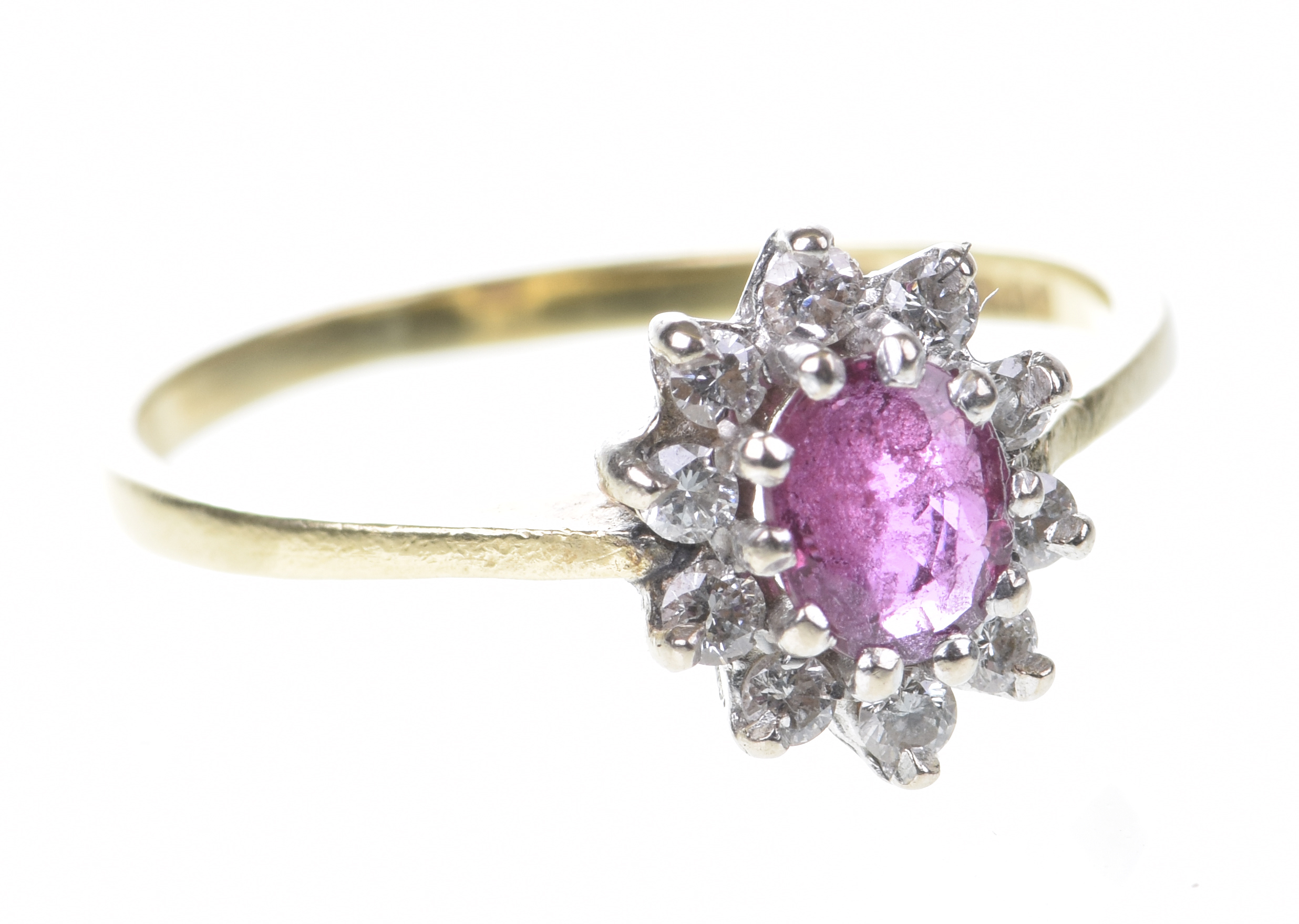 A ruby and diamond cluster ring The oval-shaped ruby to a round brilliant-cut diamond surround,