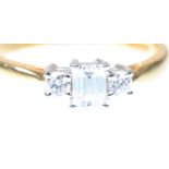 A diamond three stone ring The emerald-cut diamond flanked by two round brilliant-cut diamonds,