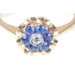 A sapphire and diamond cluster ring The collet set round brilliant-cut diamond within a