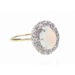 An opal and diamond cluster ring The oval opal cabochon, to an old-cut diamond surround,