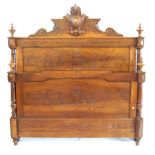 A French carved and panelled walnut double bedstead The headboard surmounted with ornate crest,