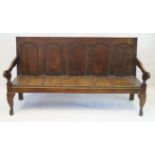 An 18th Century oak settle The five fielded panelled back above solid seat, flanked by open arms,