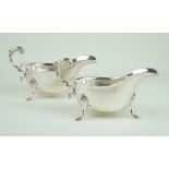 A pair of George V hallmarked silver sauce boats Each having cast rims, raised on three hoof feet,