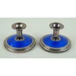 A pair of sterling silver and blue guilloche enamelled candlesticks Of circular squat form,