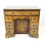 A Georgian style cross banded and figured walnut veneered kneehole desk,