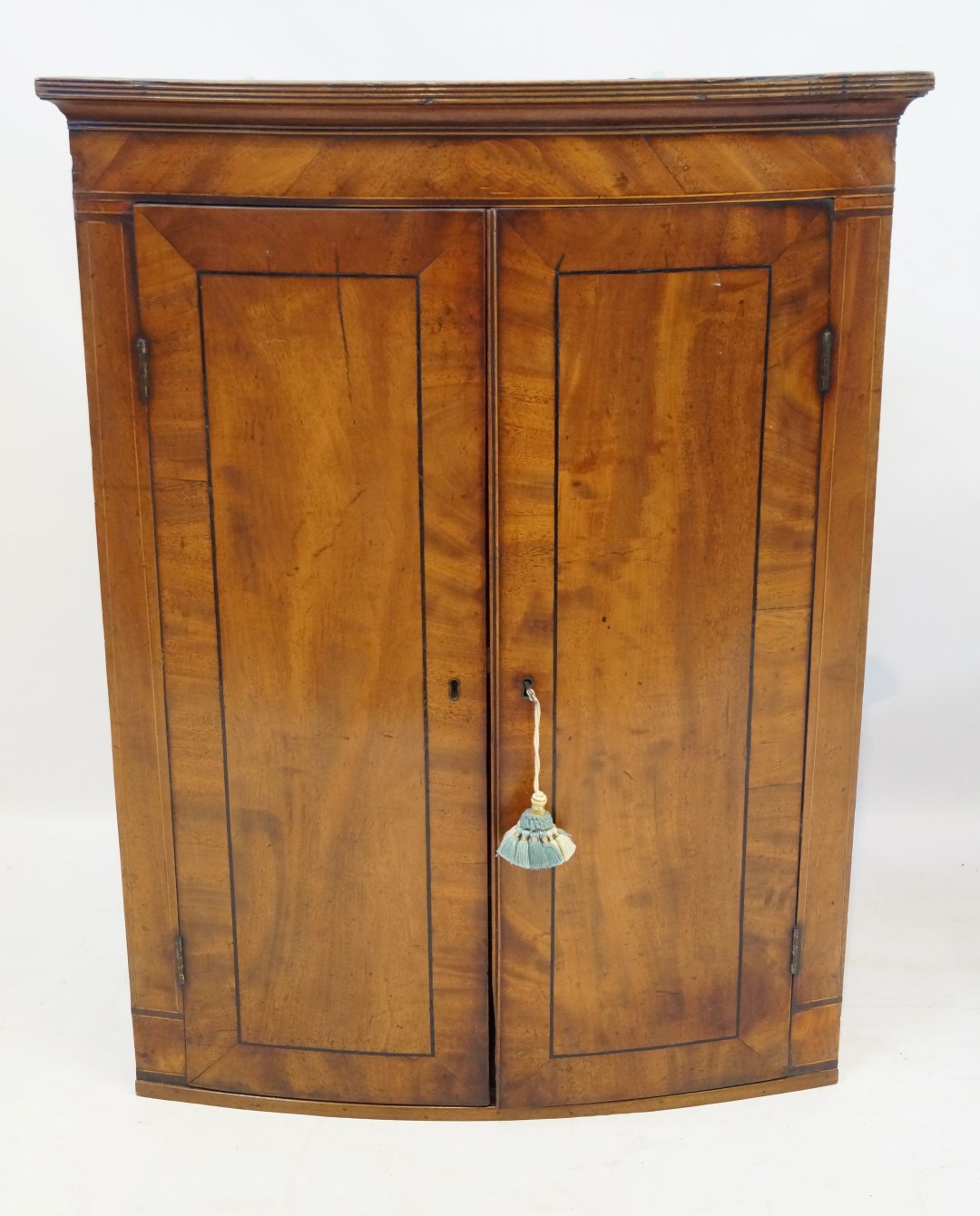A George III inlaid and crossbanded mahogany bowfront hanging corner cupboard The moulded cornice