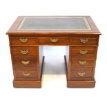 An Edwardian walnut kneehole pedestal desk The rectangular top with inset gilt tooled green