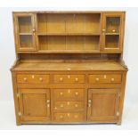 A Victorian stripped pine dresser The raised back featuring glazed panelled doors and open shelves,