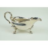 A George II hallmarked silver sauce boat Of plain form, with cast rim, raised on three hoof feet,