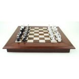 A contemporary mahogany chess board With a clear and black glass chess set,