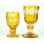 Two Bohemian amber glass pedestal goblets Each having engraved panelled decoration depicting