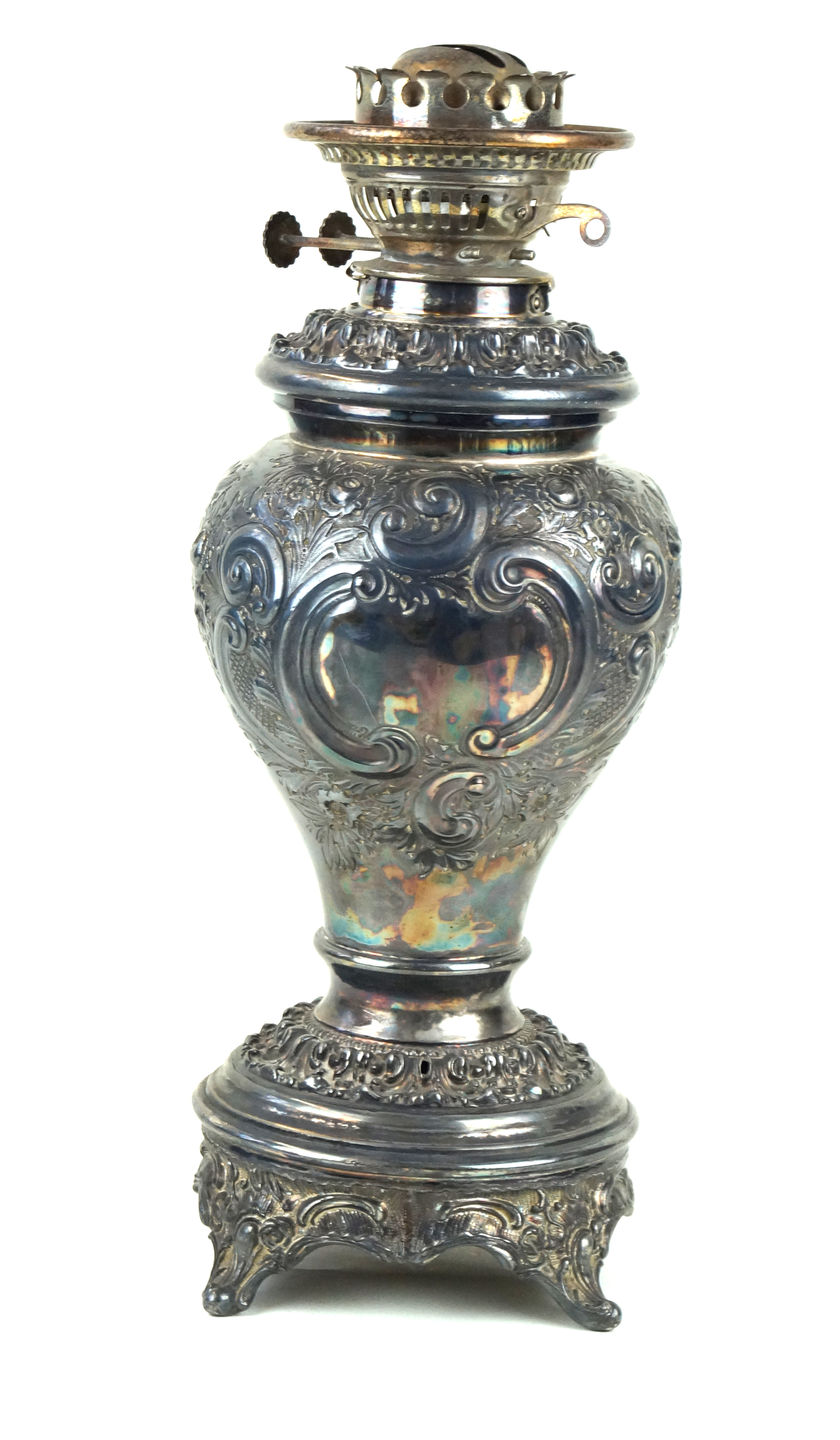 A late 19th/early 20th Century silver-plated paraffin lamp Repousse decorated with scrolls and