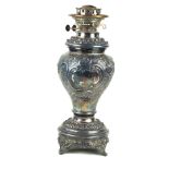 A late 19th/early 20th Century silver-plated paraffin lamp Repousse decorated with scrolls and