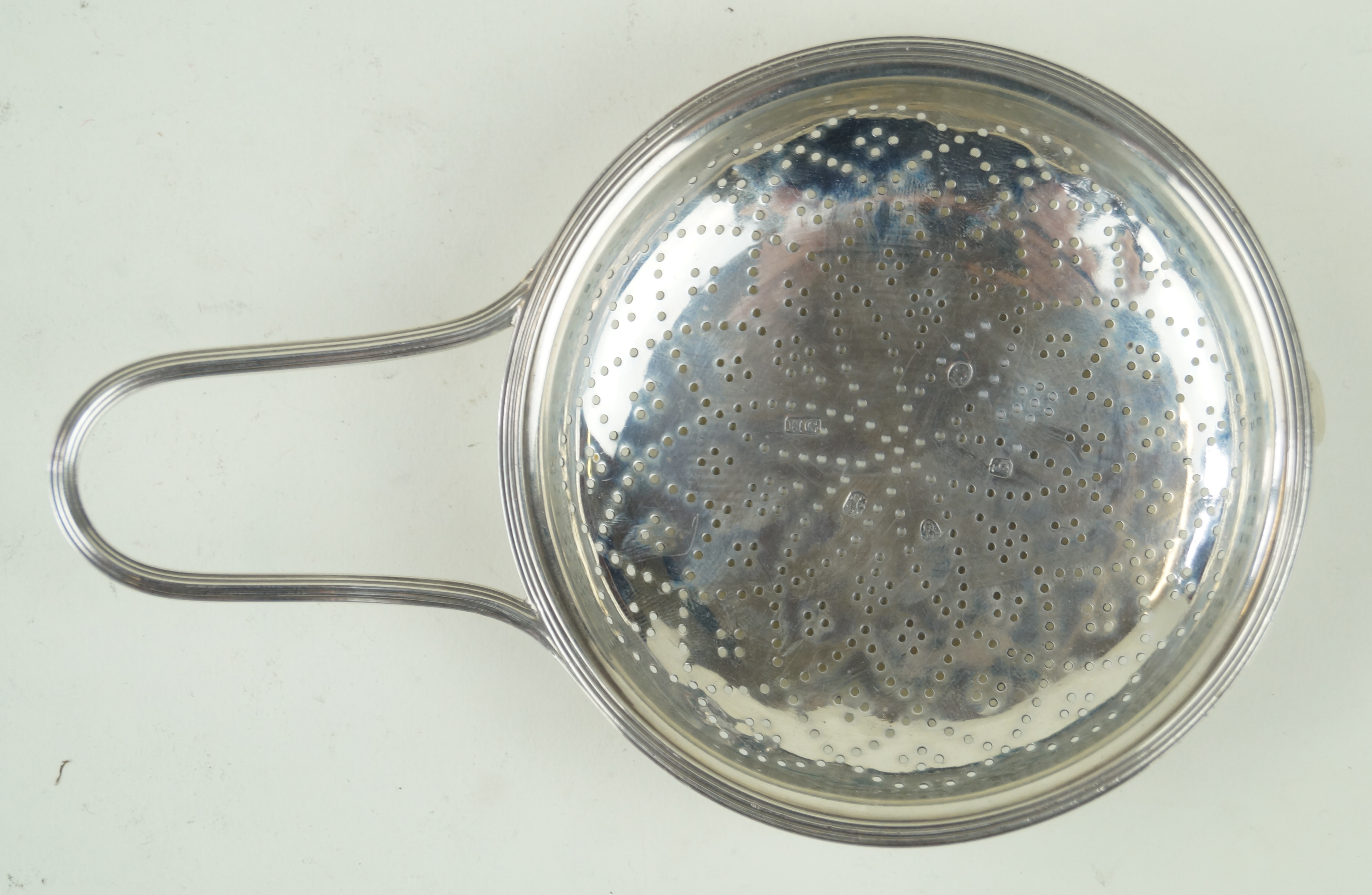 A George III hallmarked silver orange strainer The typical bun shaped bowl with single handle,