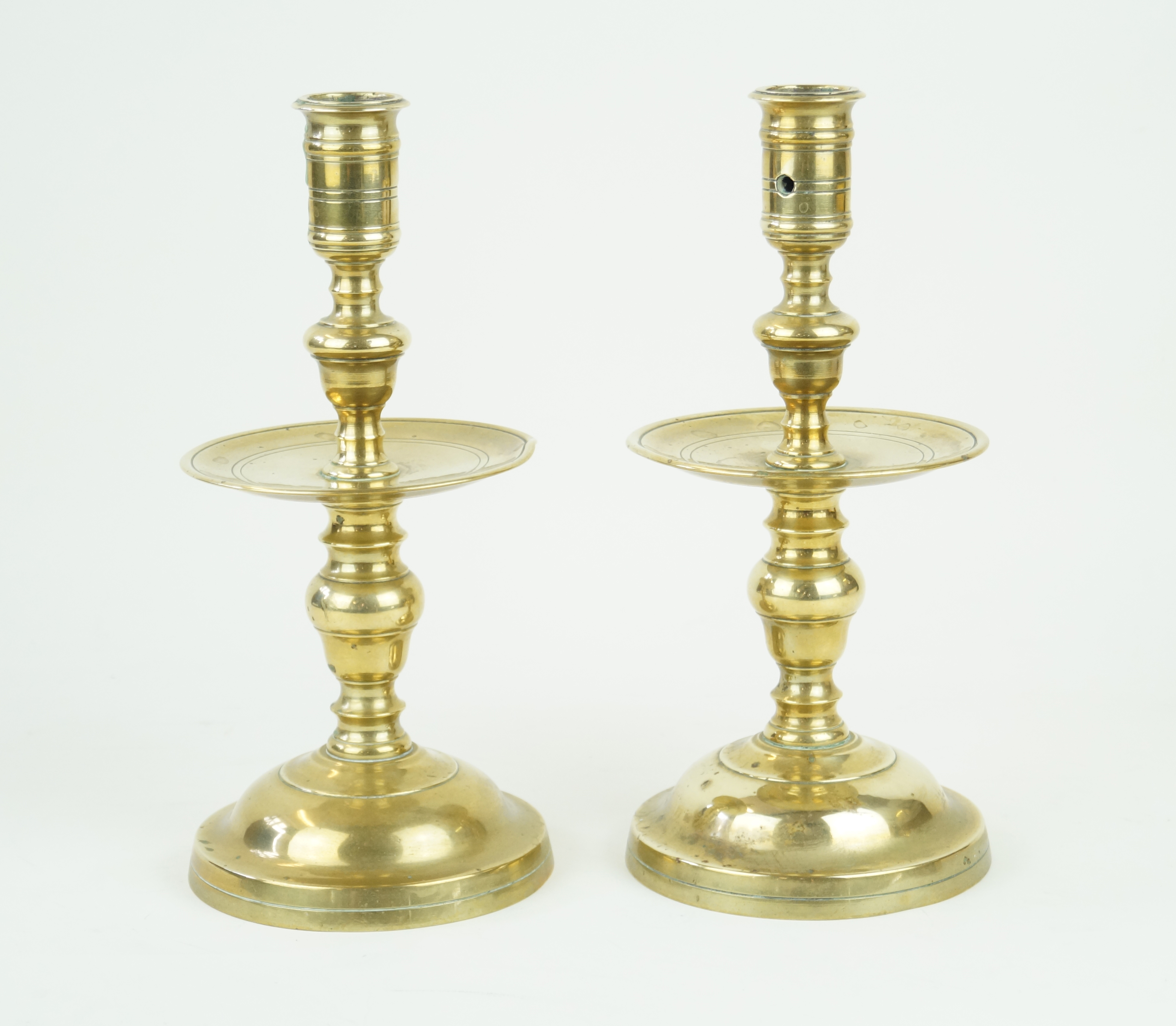 A pair of Dutch brass candlesticks, 19th Century Each modelled with large drip trays,