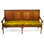 An 18th Century oak settle The raised back featuring four mahogany banded shaped fielded panels,