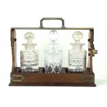 An early 20th Century mahogany framed three bottle Tantalus Having silver-plated and chrome mounts,