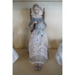 A large Lladro figure depicting a seated lady with embroidery.