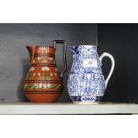 An Art and Crafts terracotta jug in the manner Dr Christopher Dresser together with a further blue