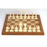 An early 20th Century ivory chess set Complete, one set with green stained linear motifs to bases,