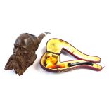 Two Meerschaum pipes To include a carved wooden example depicting an elderly gentleman with beard,