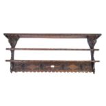 An antique carved oak plate rack in the Flemish taste The shaped canopy and fixed shelf above