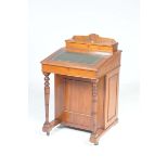 An Edwardian walnut Davenport The hinged rectangular top with a flower head crest enclosing a